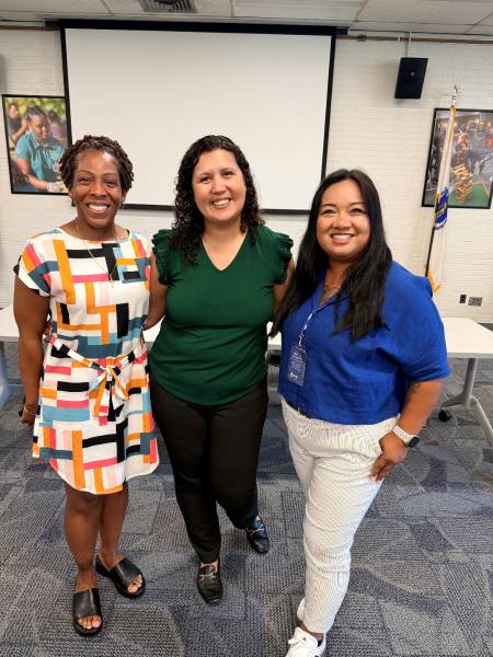 Three women posing together at a symposium style event.