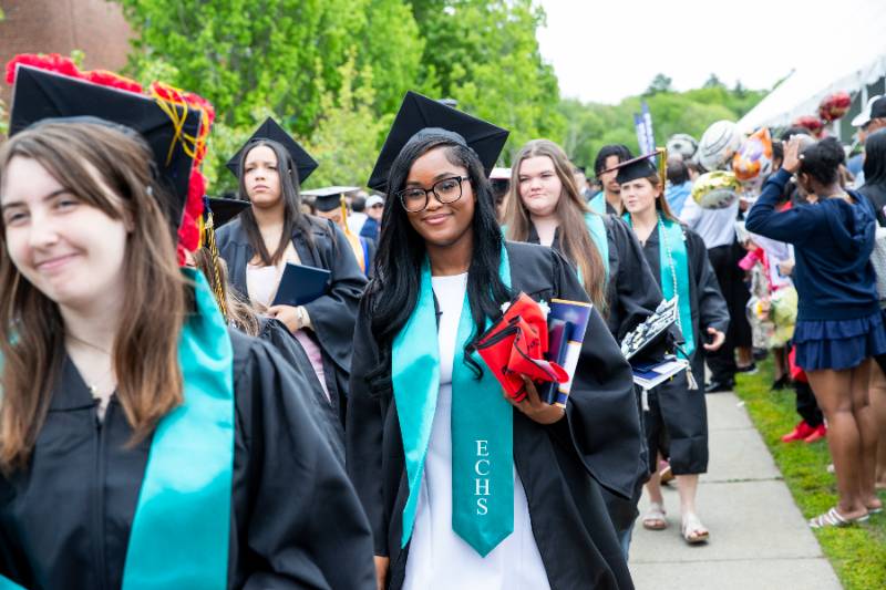 Graduates walking out of a commencement tent.