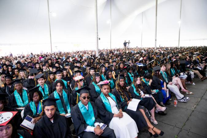 Graduates sitting under a Commencement tent.