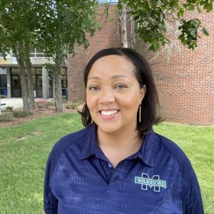 Photo of Erica Rivers, Director of Athletics at Massasoit Community College. Posing in front of the Peter Asiaf Field House