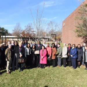 Ifill stands with family, Probation Service colleagues, current and former trustees, and Massasoit staff at the tree dedicated in his honor.