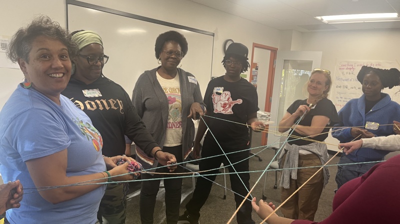 Group of people holding intersecting string.