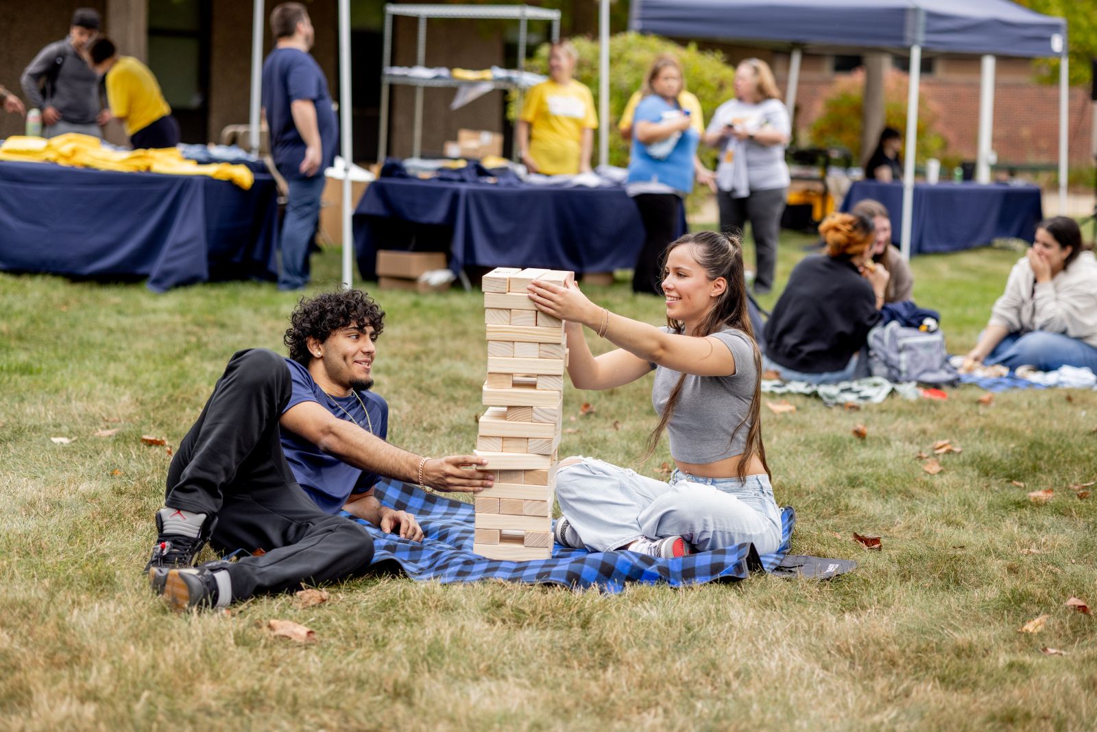 Students playing Jenga on a picnic blanket.